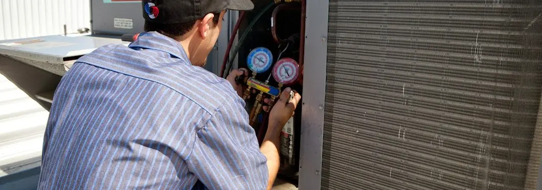 HVAC technician servicing a condenser unit in Ozark